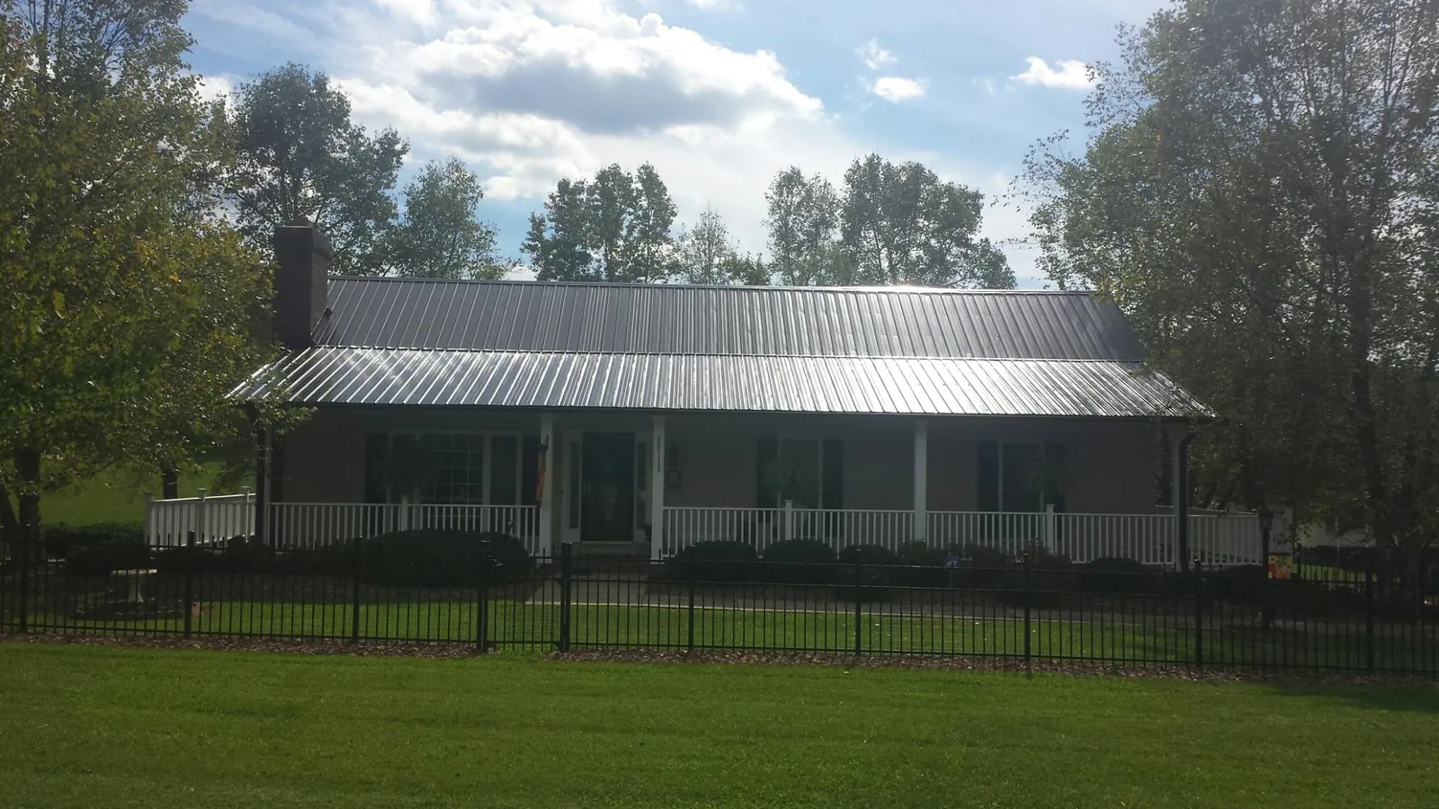 Gray metal roof on a brick ranch with a full width front porch — Gutter Guard Installation work by our crew in Graysville